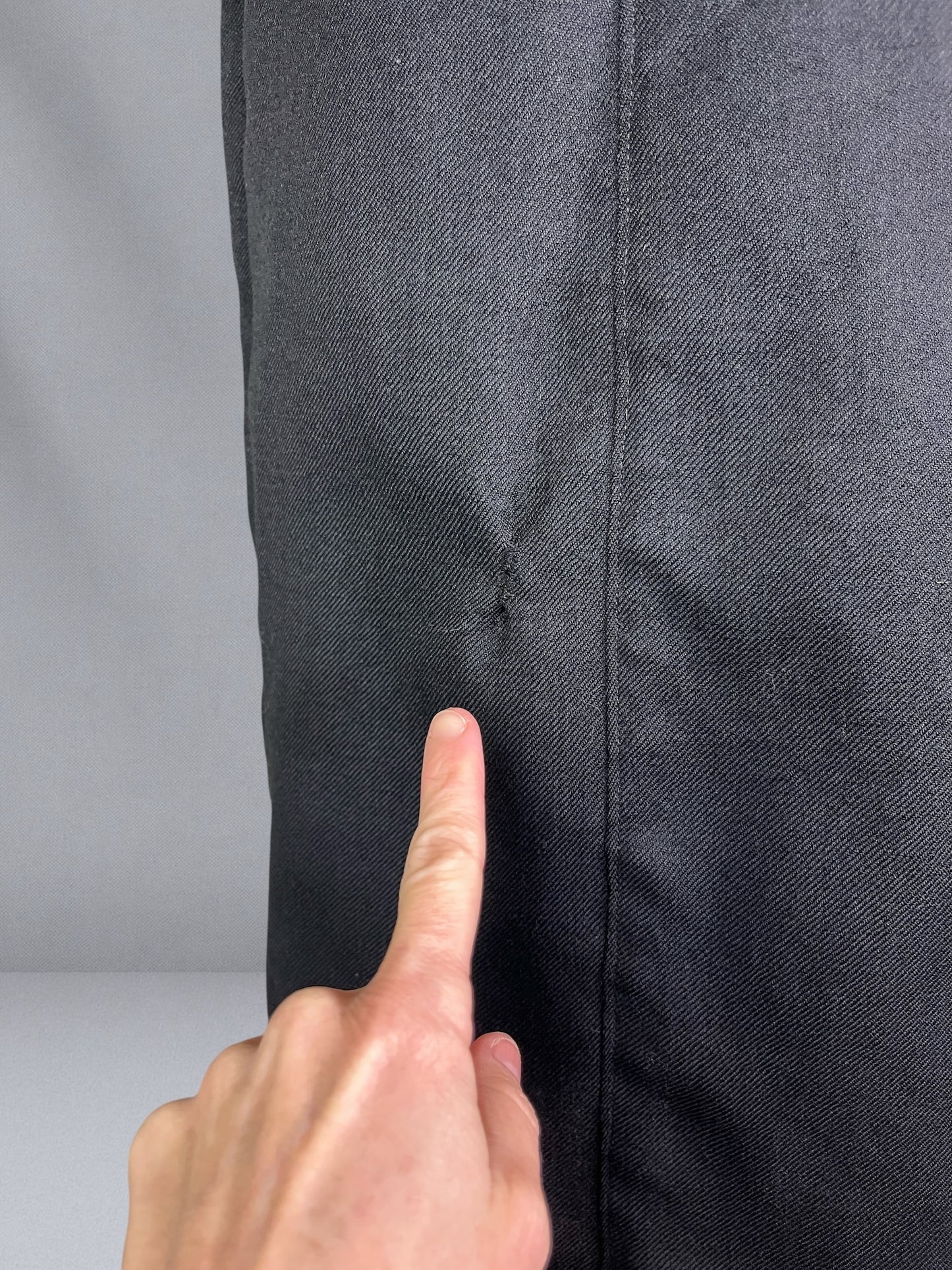 finger pointed to small darn on coat