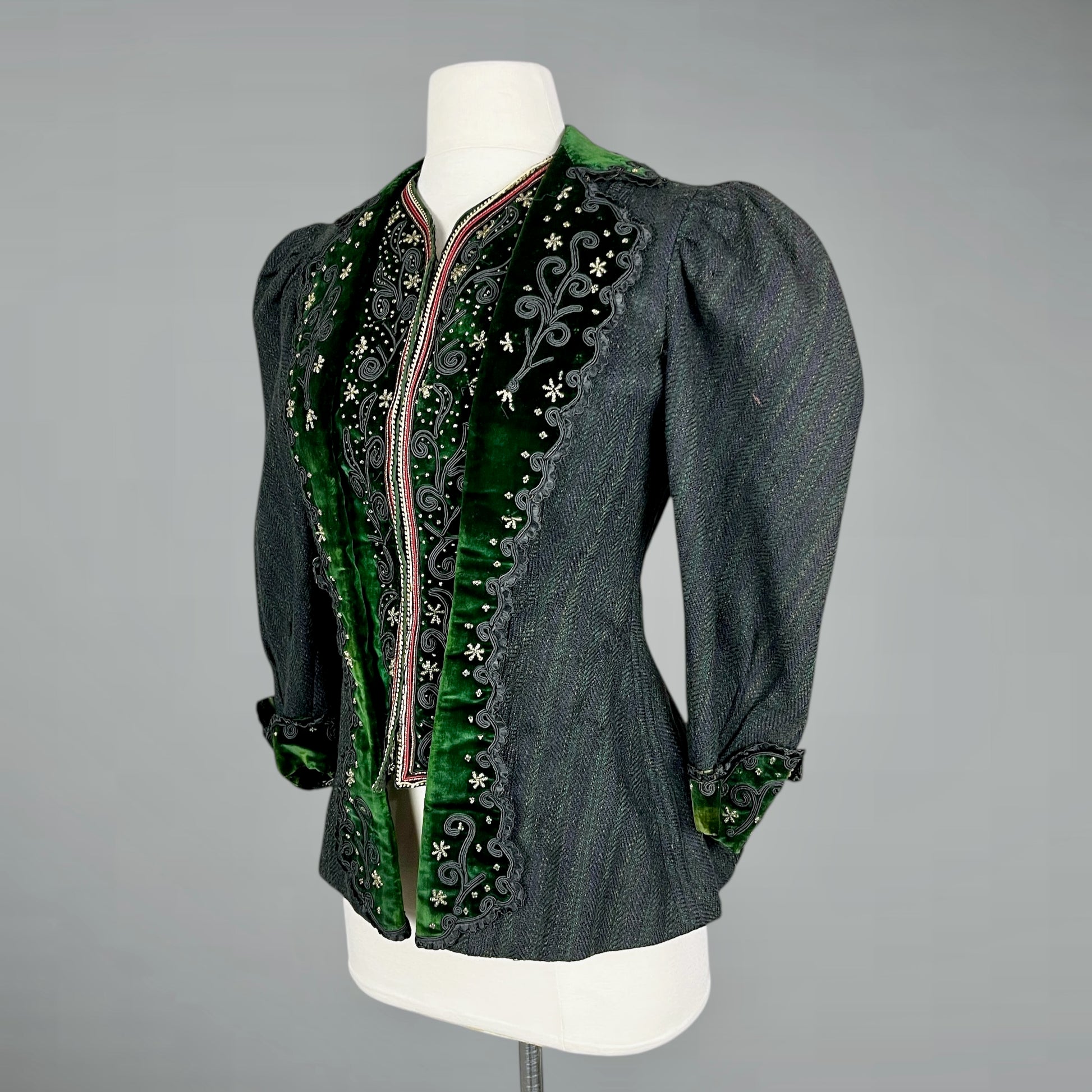 Antique wool bodice jacket with green velvet trim on a mannequin against a gray background