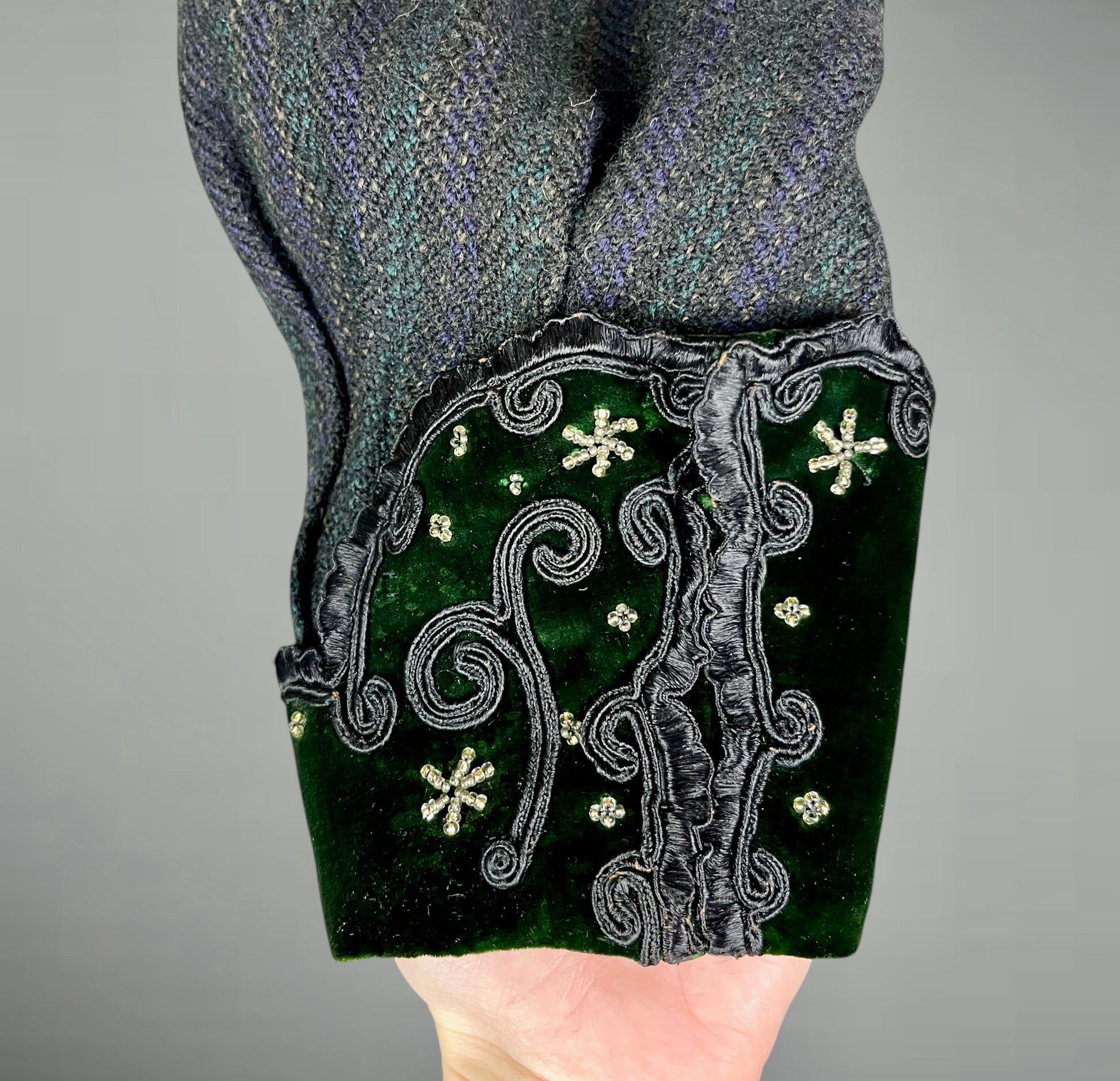 Close-up of a green embroidered cuff with soutache trim and beadwork